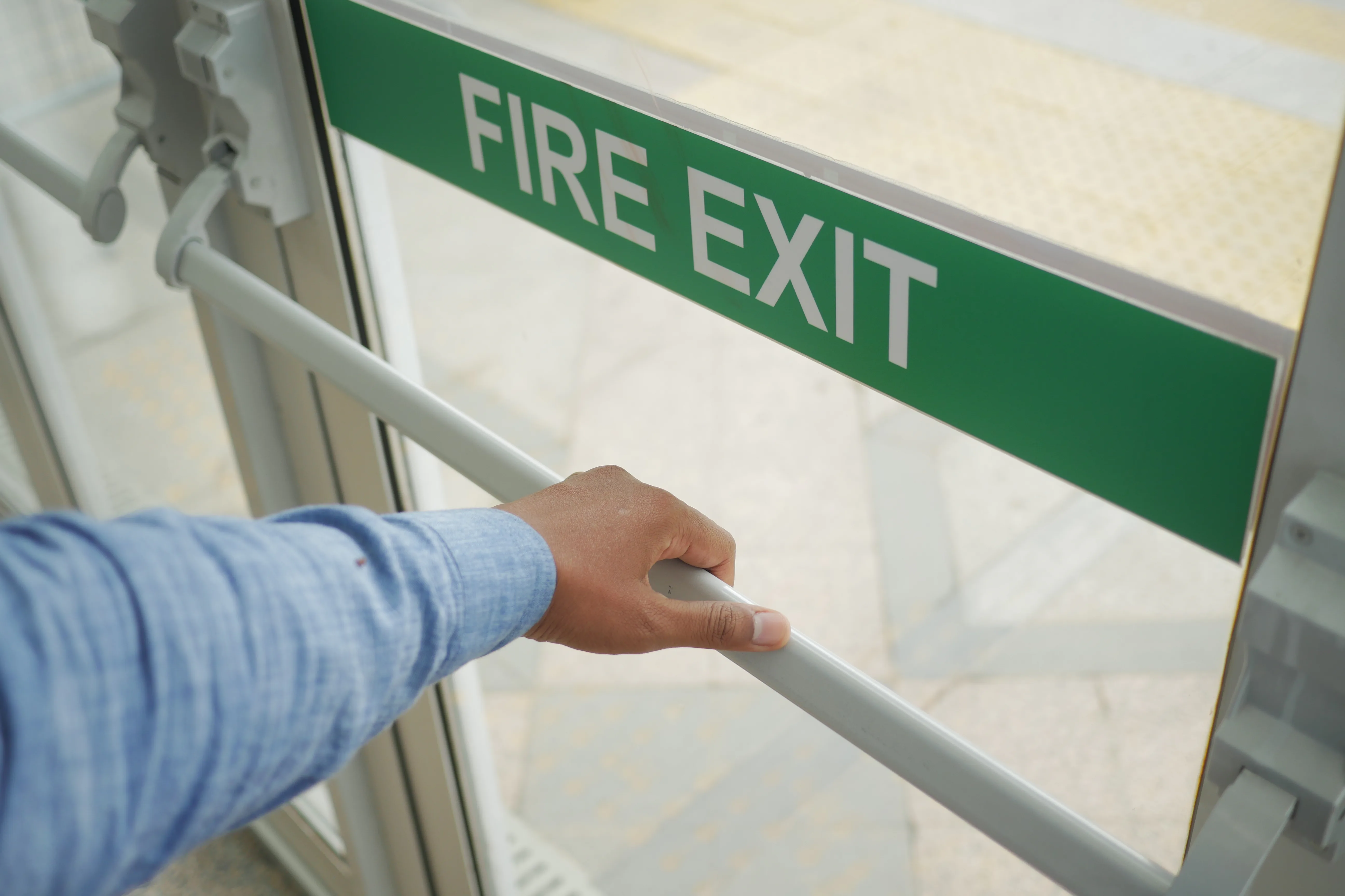 Person pushing a fire exit door bar