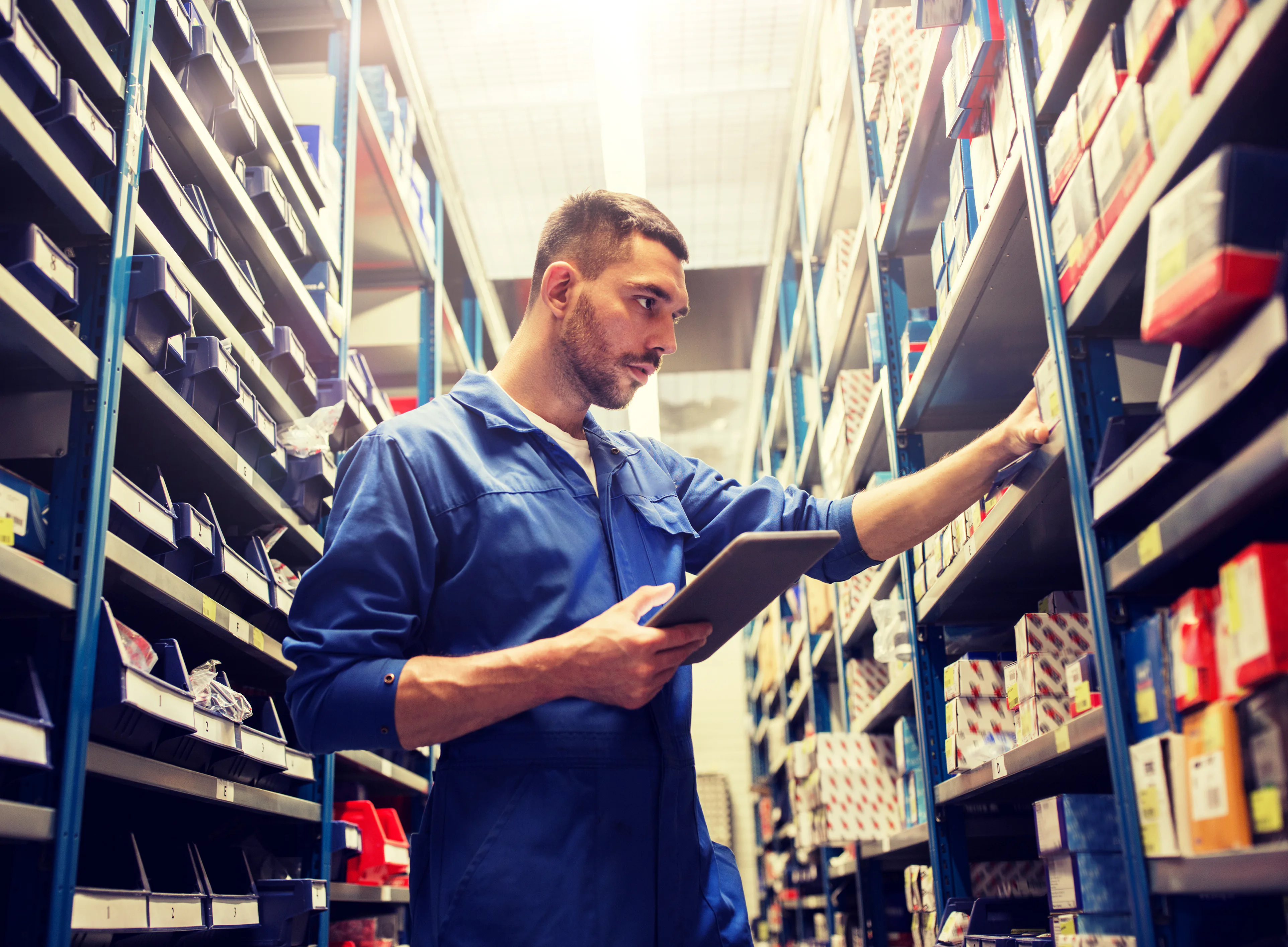 Engineer checking parts stock on a tablet in a warehouse